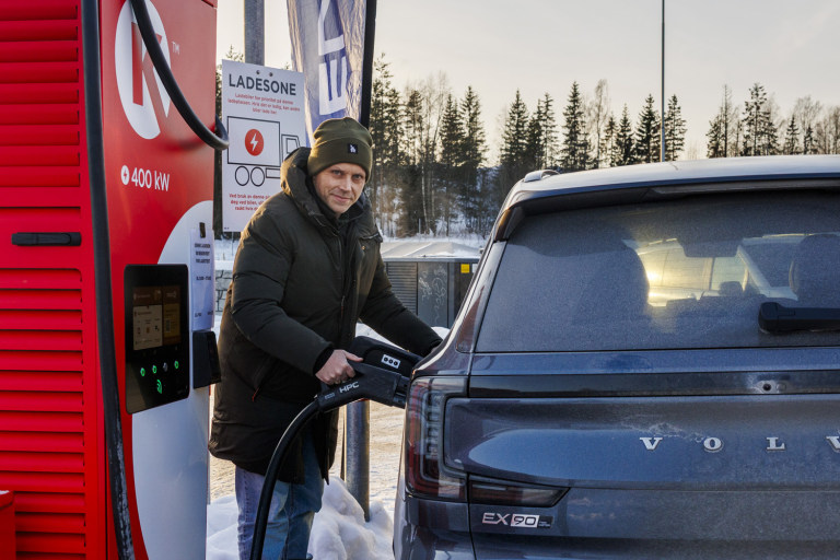 Mann holder ladepistol ved bilen
