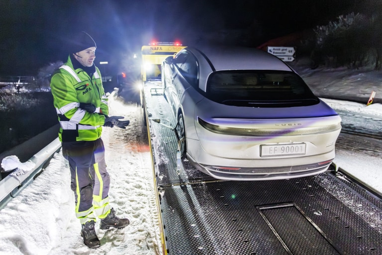 Hvit sedan på lasteplanet til bilberger
