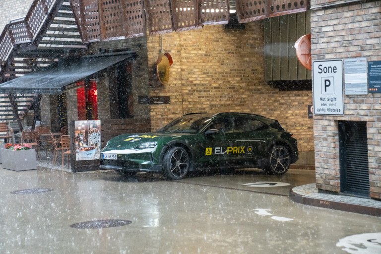 Grønn Porsche Taycan kjører ut av parkeringshus