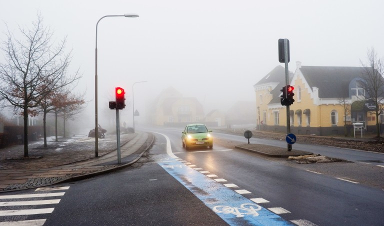 Bil står stille i trafikkryss mens den venter på grønt lys.