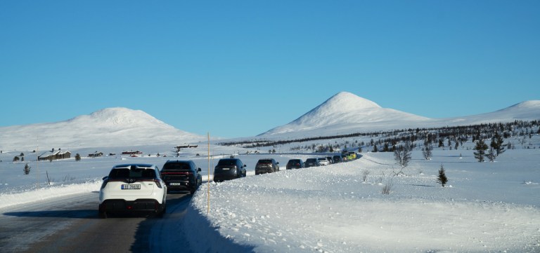 Elbiler kjører etter hverandre på snødekte fjell