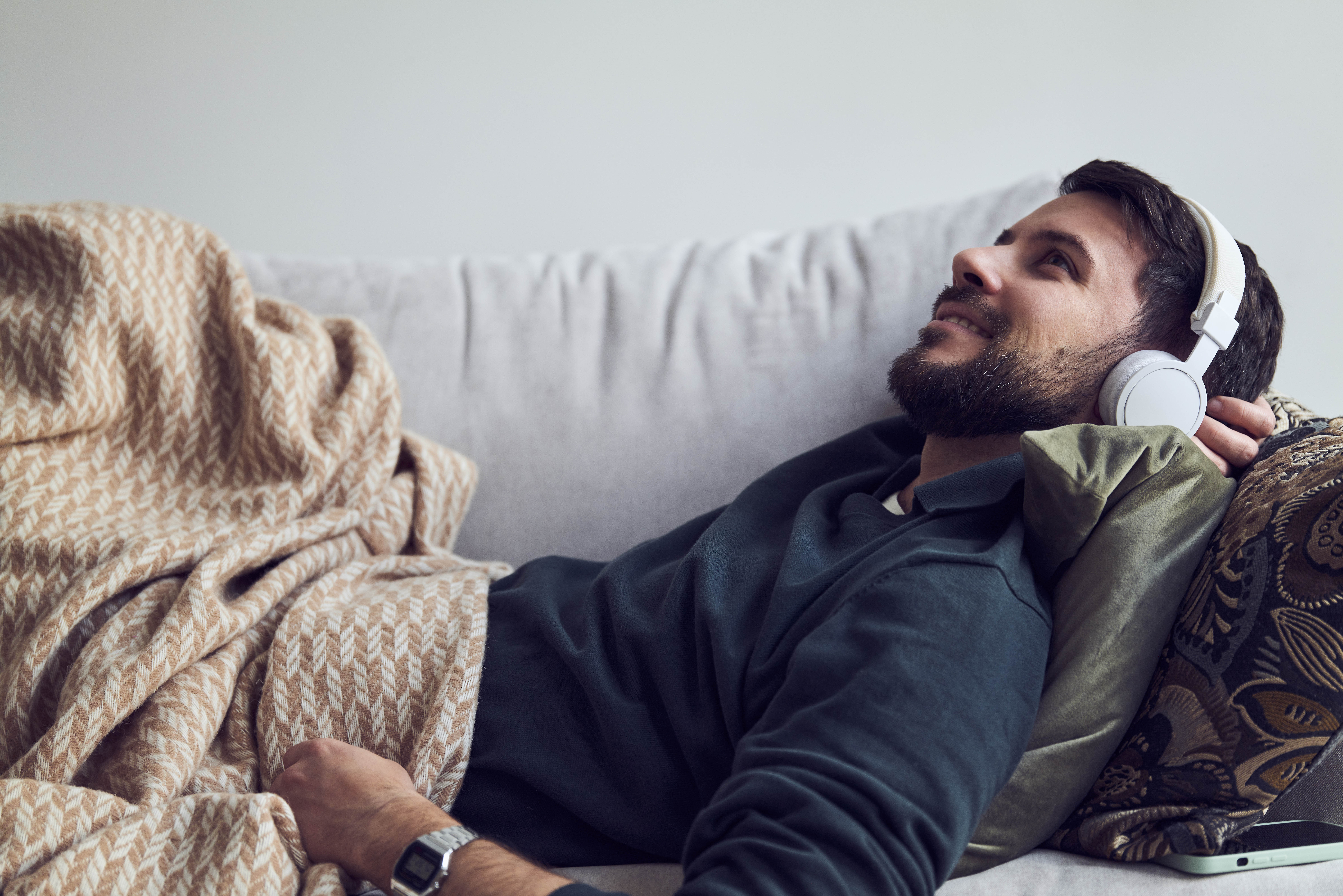 Mann ligger på sove under pledd og lytter til Fabel
