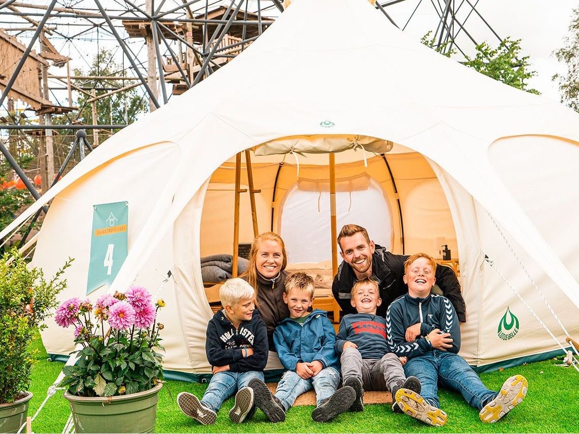 Bildet viser en smilende familie som skal overnatte i glampingtelt i Brumlecamp