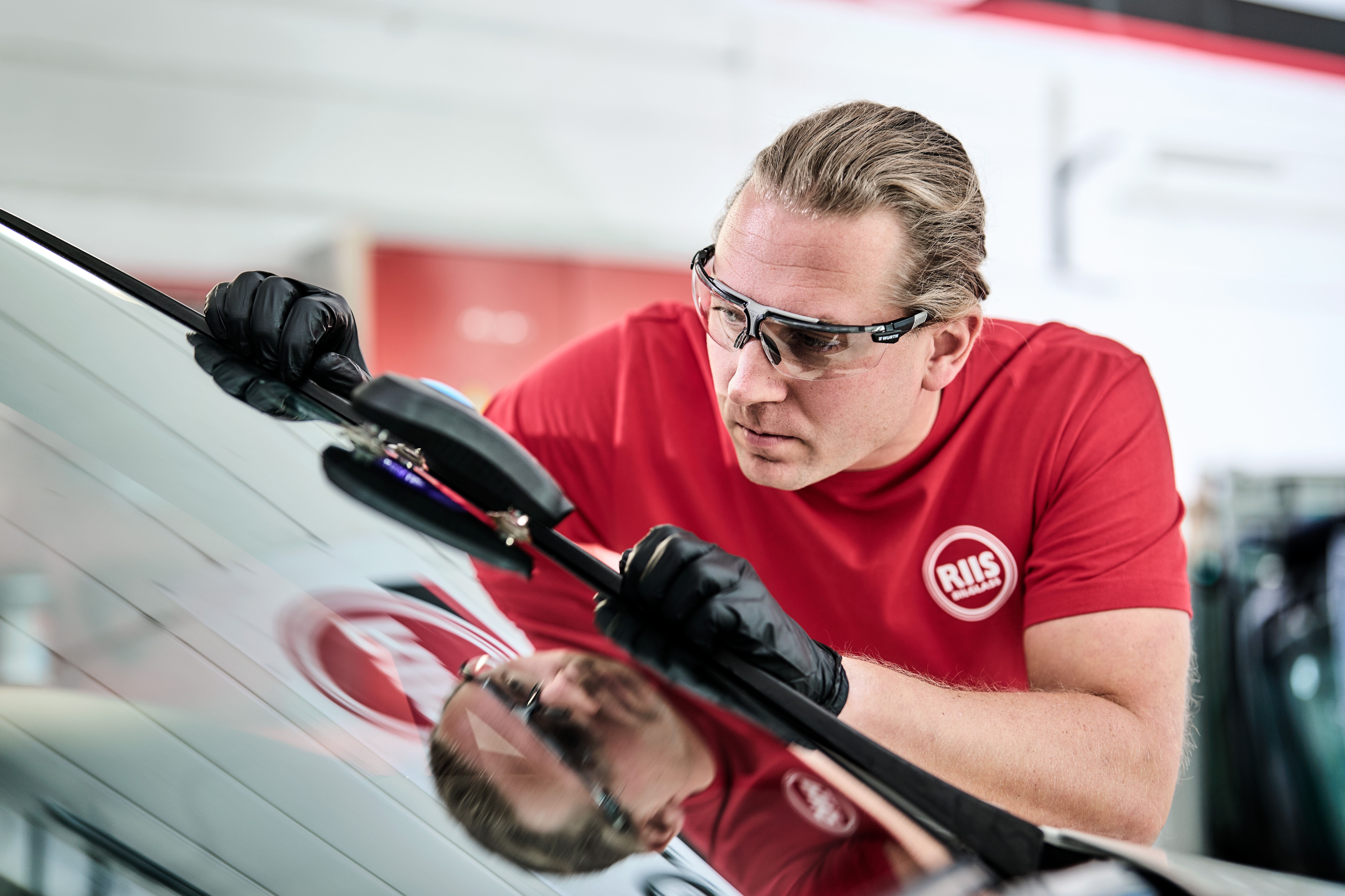 Mann som reparerer steinsprutskade på frontrute