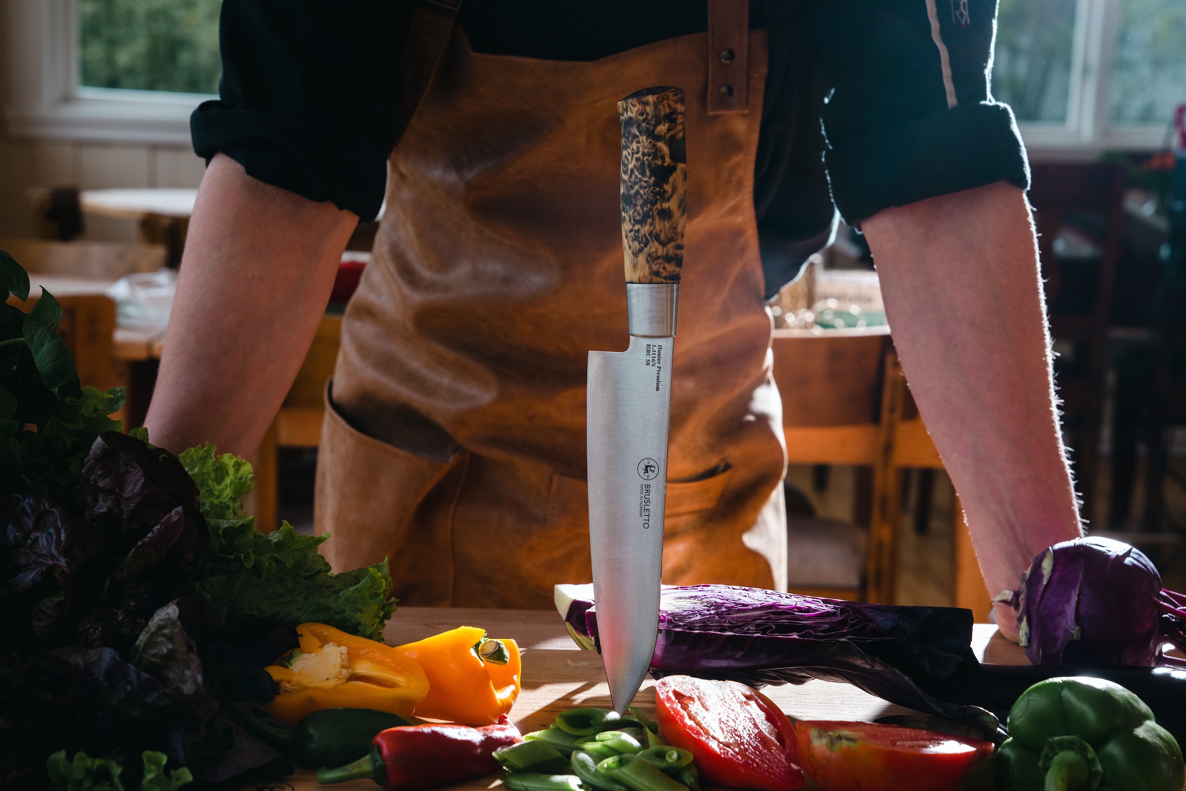 Kjøkkenkniv i skjærebrett med kokken i bakgrunn