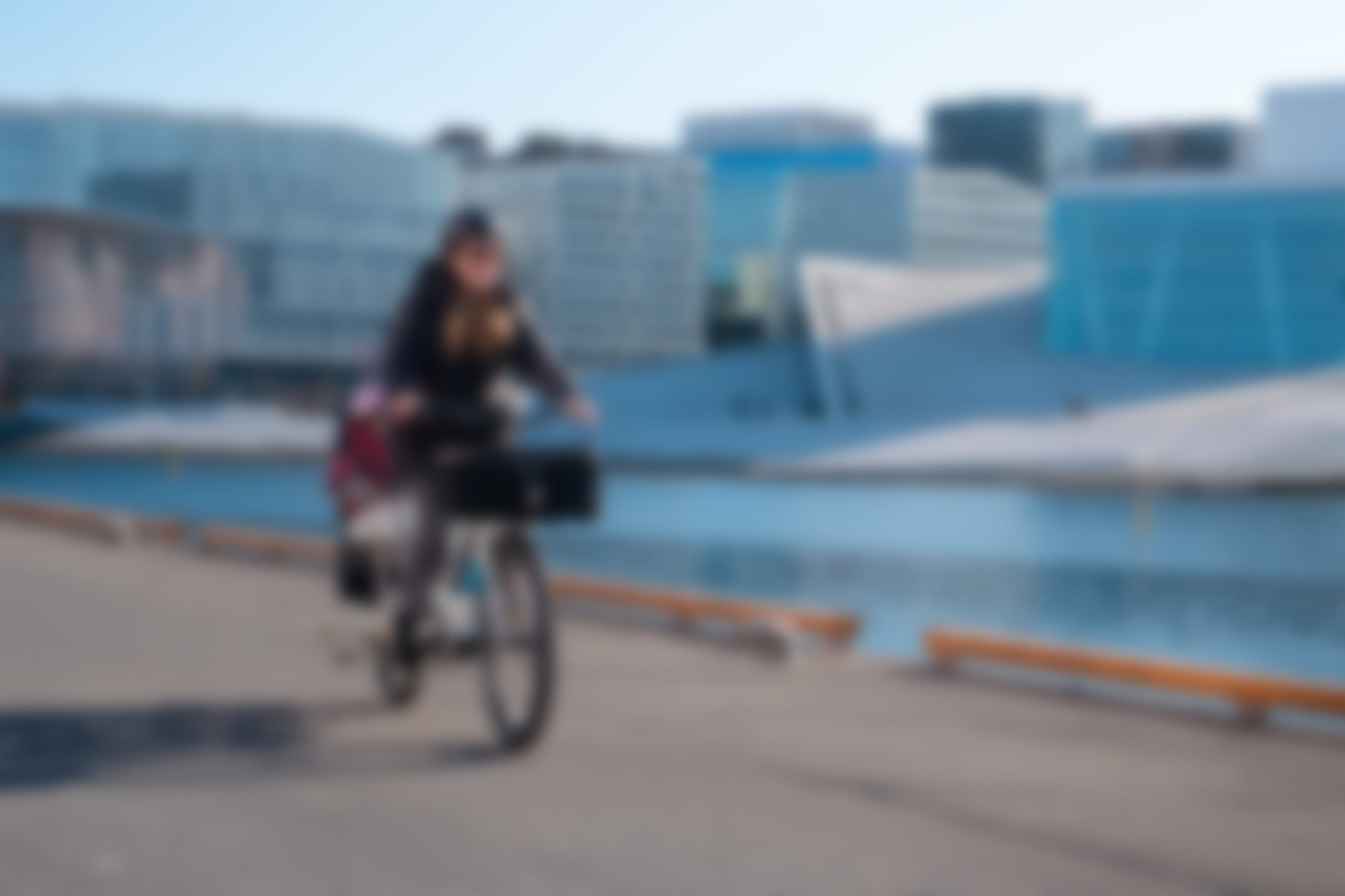Bilde av en dame som sykler på en elsykkel langs brygga ved Operaen.