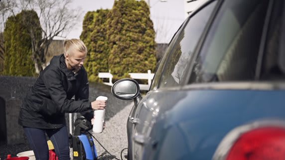 bildet viser en dame som spruter avfettingsmiddel på bilen.