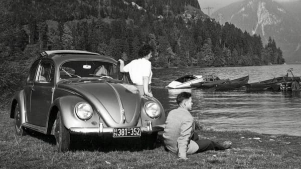 En kvinne og en mann ser ut over en innsjø. Bak dem er en bil parkert.
