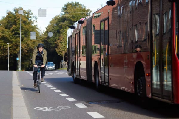 Syklist sykler i sykkelfeltet og buss passerer 