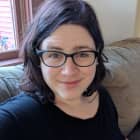 Kat Champigny smiling and sitting on a sofa