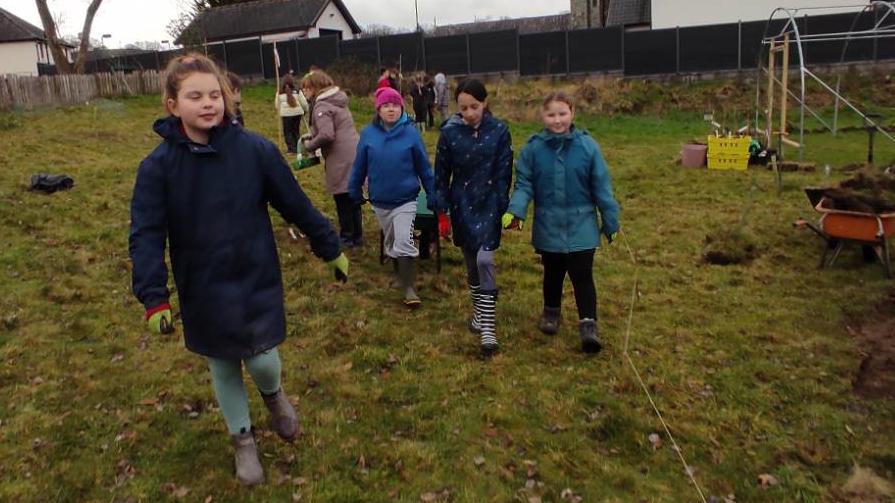 Group of students testing the curve of the footpath with a wheelbarrow