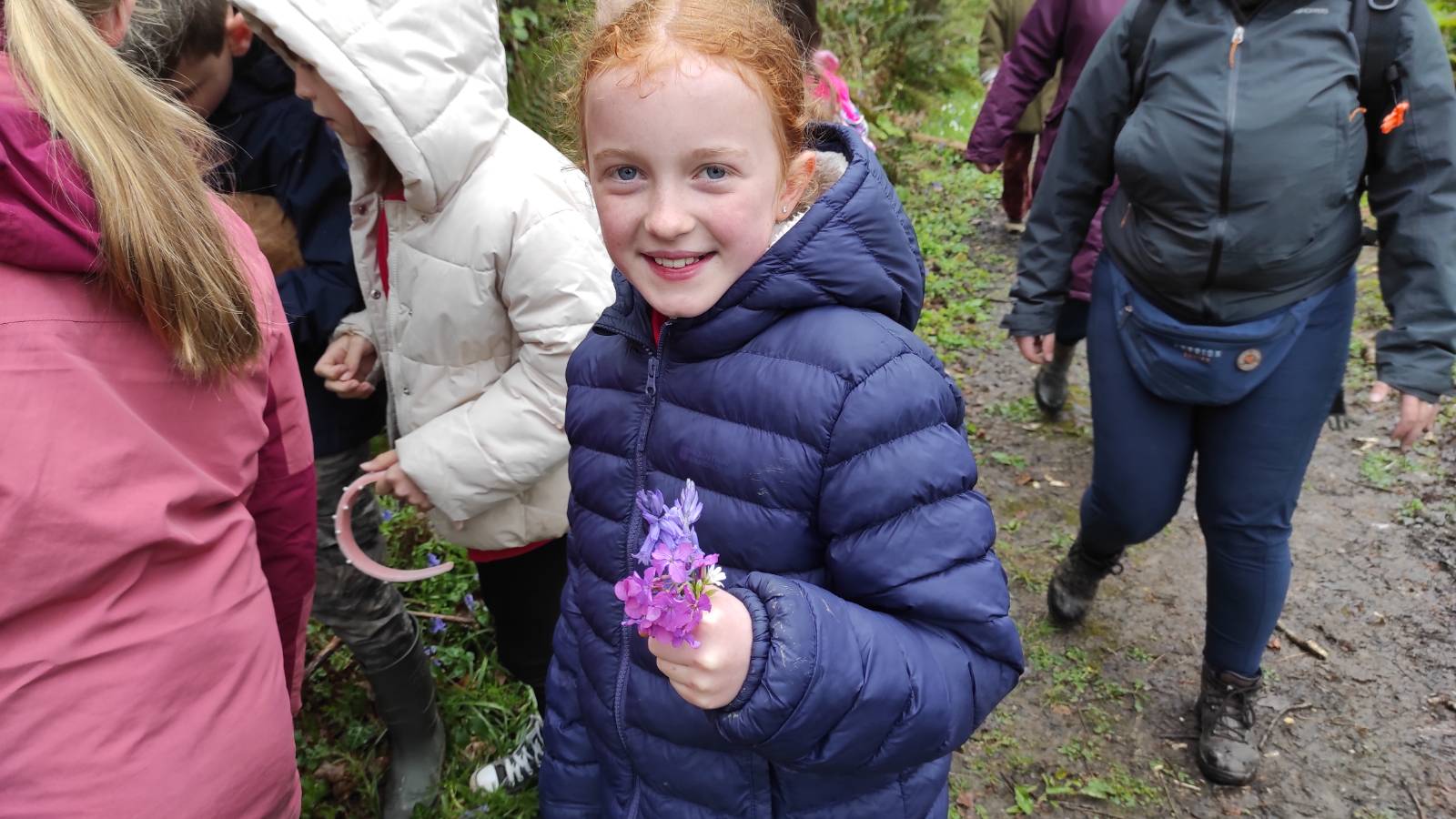 Student holding a posy of Bluebell, Honesty and Greater Stitchwort. 