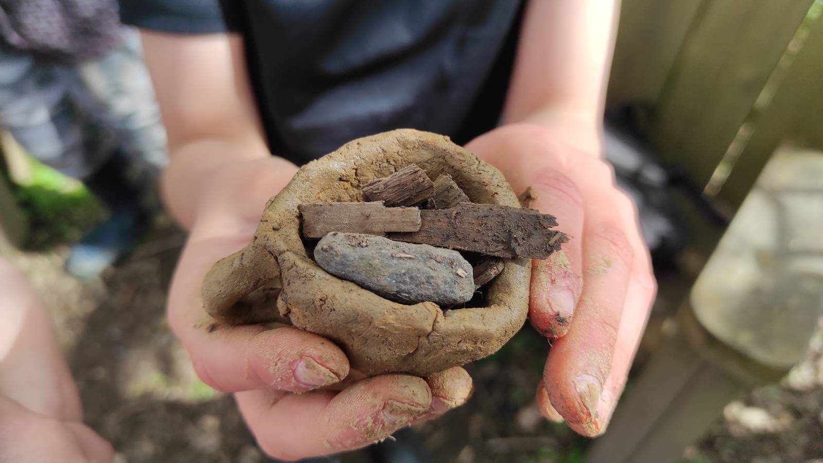 Student with clay bowl filled with sticks and stones.