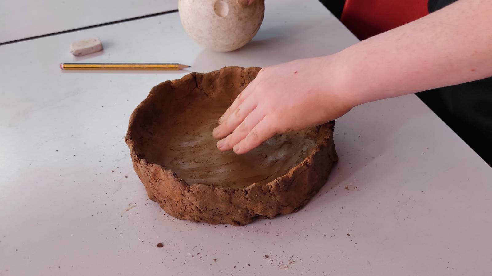 Student smoothing out their clay bowl.