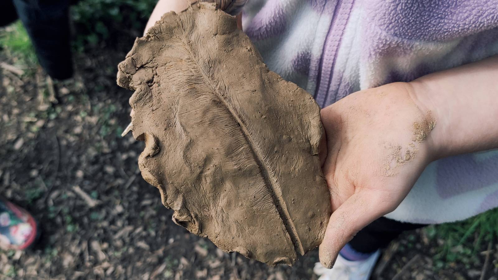 Student with clay imprint of feather.