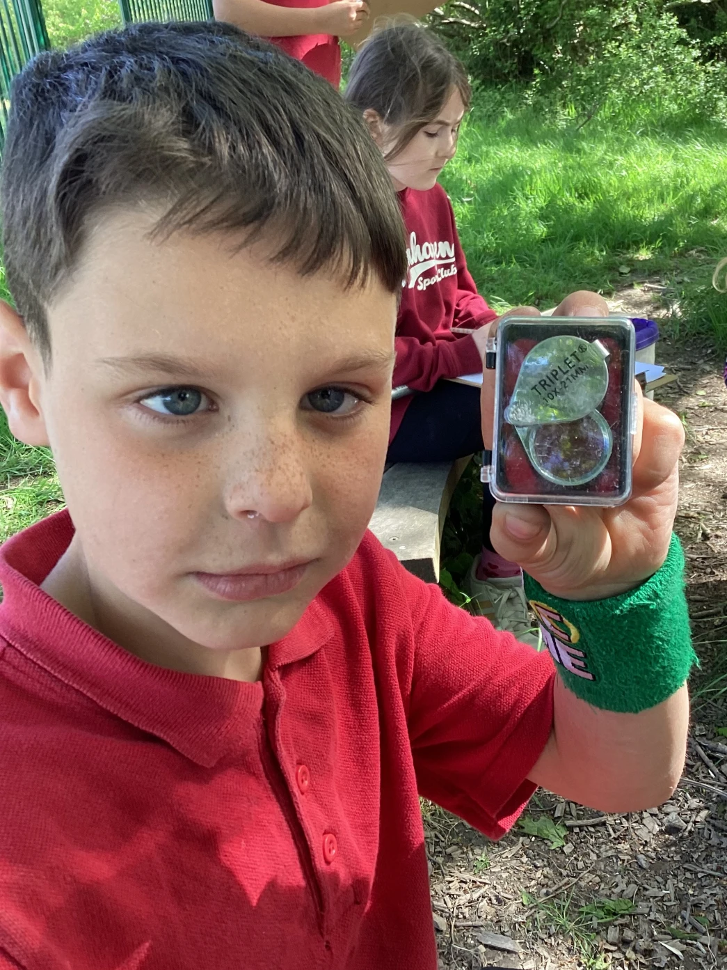 Student showing hand lens in its case