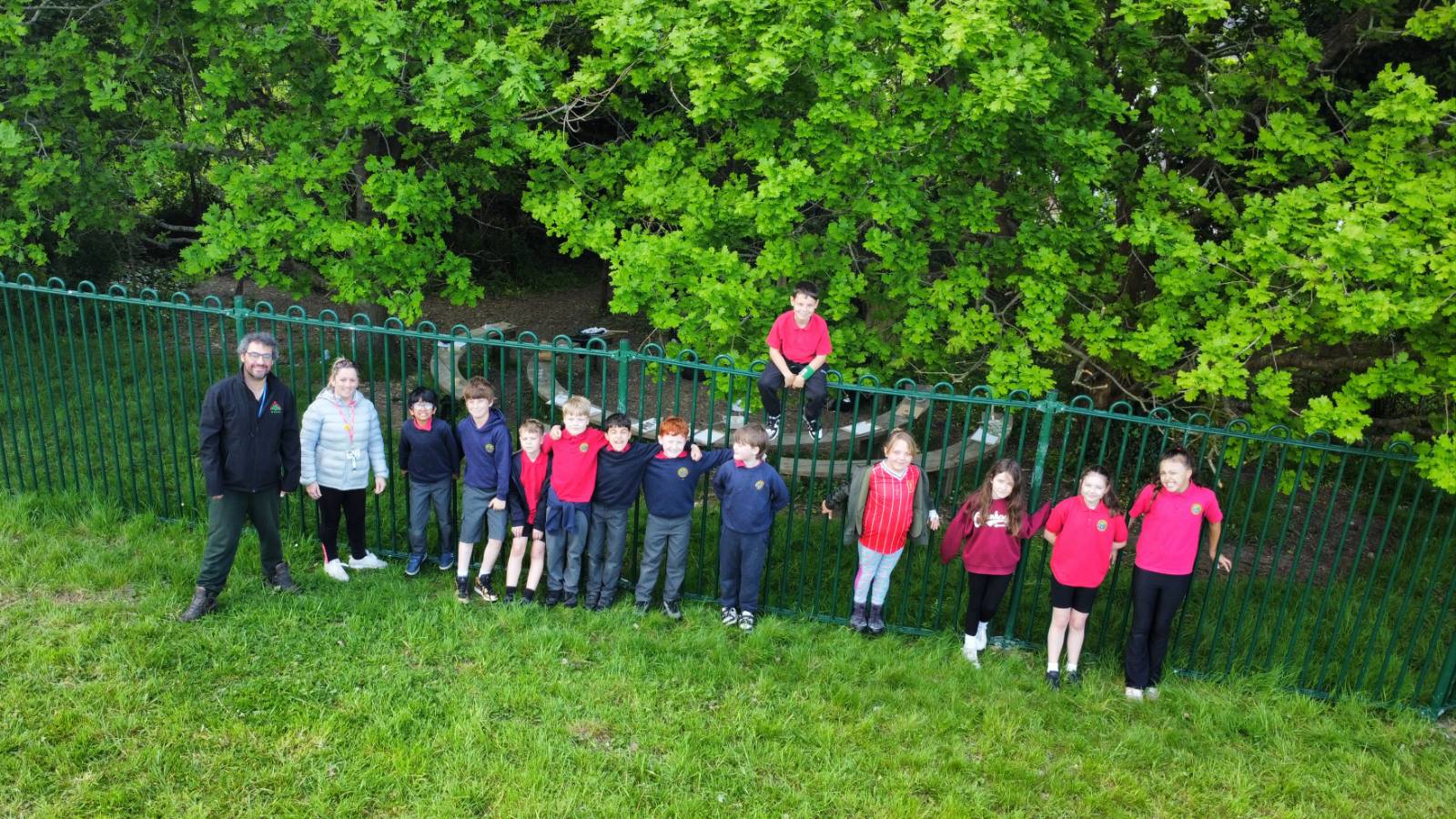 Drone photo of line of students and staff along fence by the Oaks