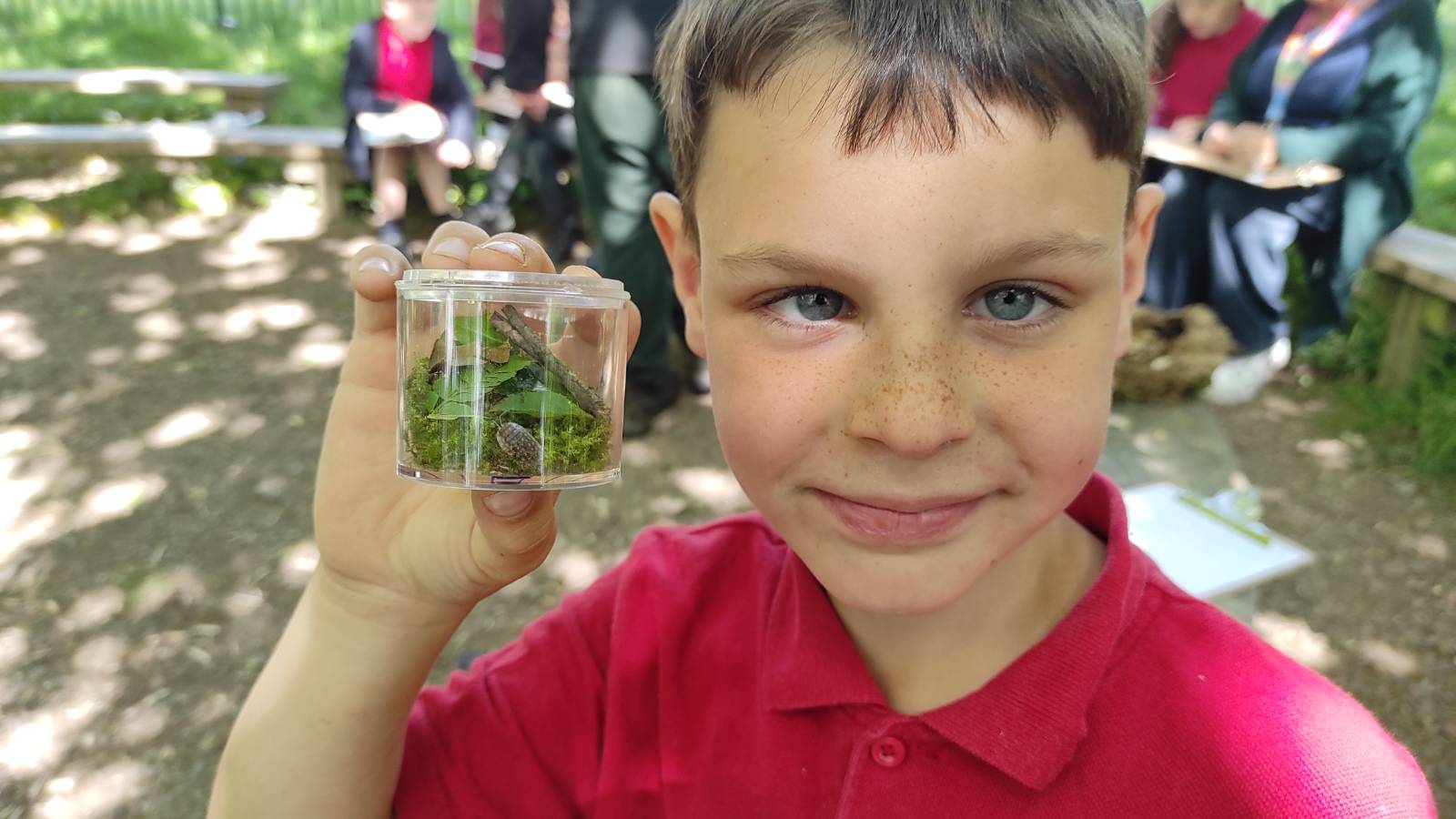 Student holding a bug pot filled with leaves and woodlice