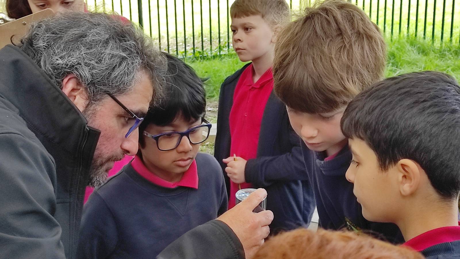 Ecologist showing students something in a bug pot