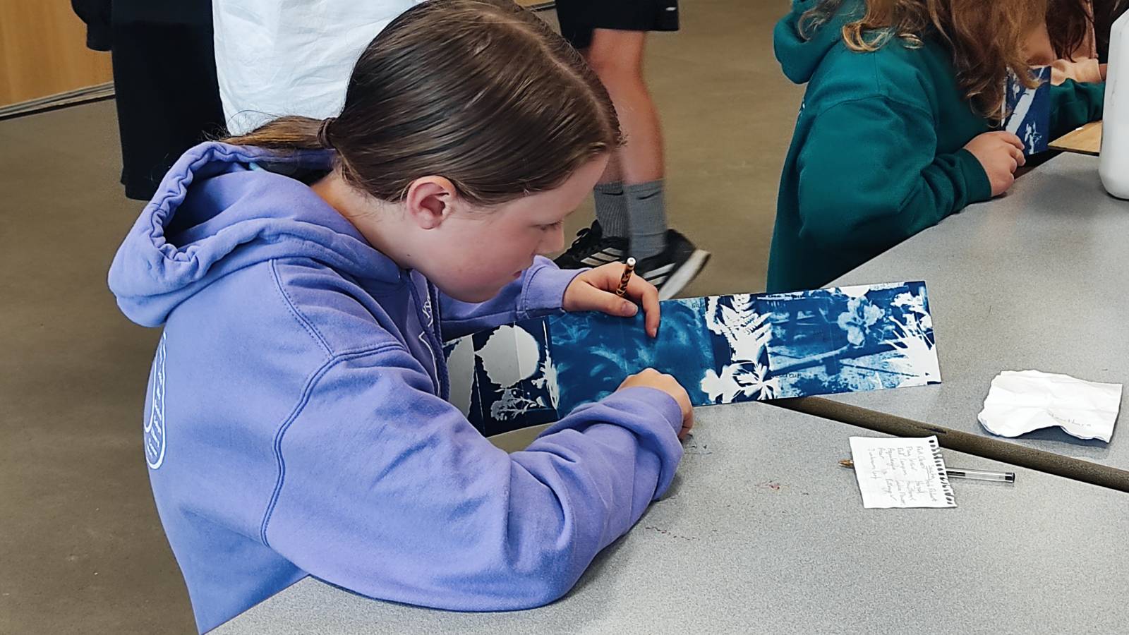 Student writing plant names on cyanotype strip