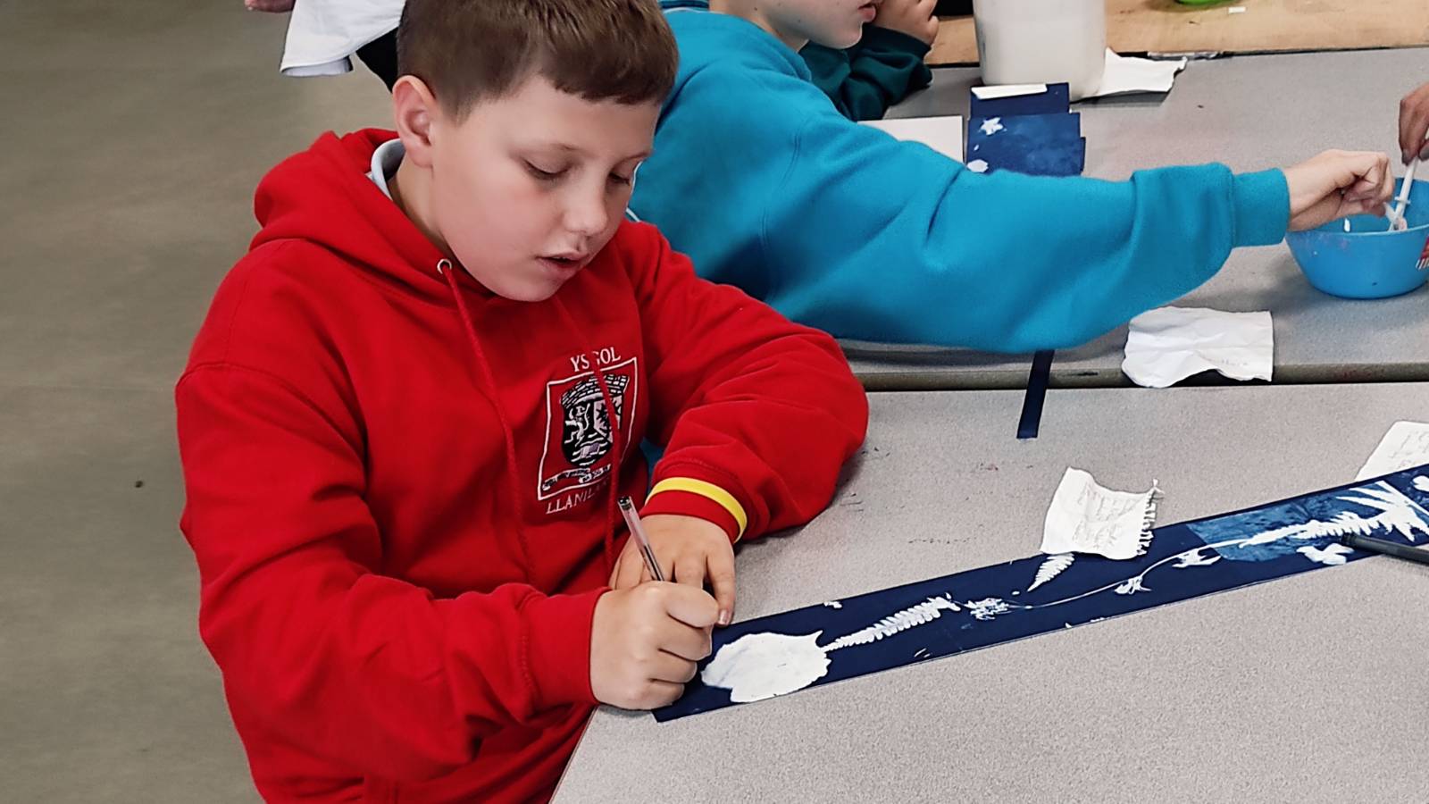 Student writing plant names on cyanotype strip