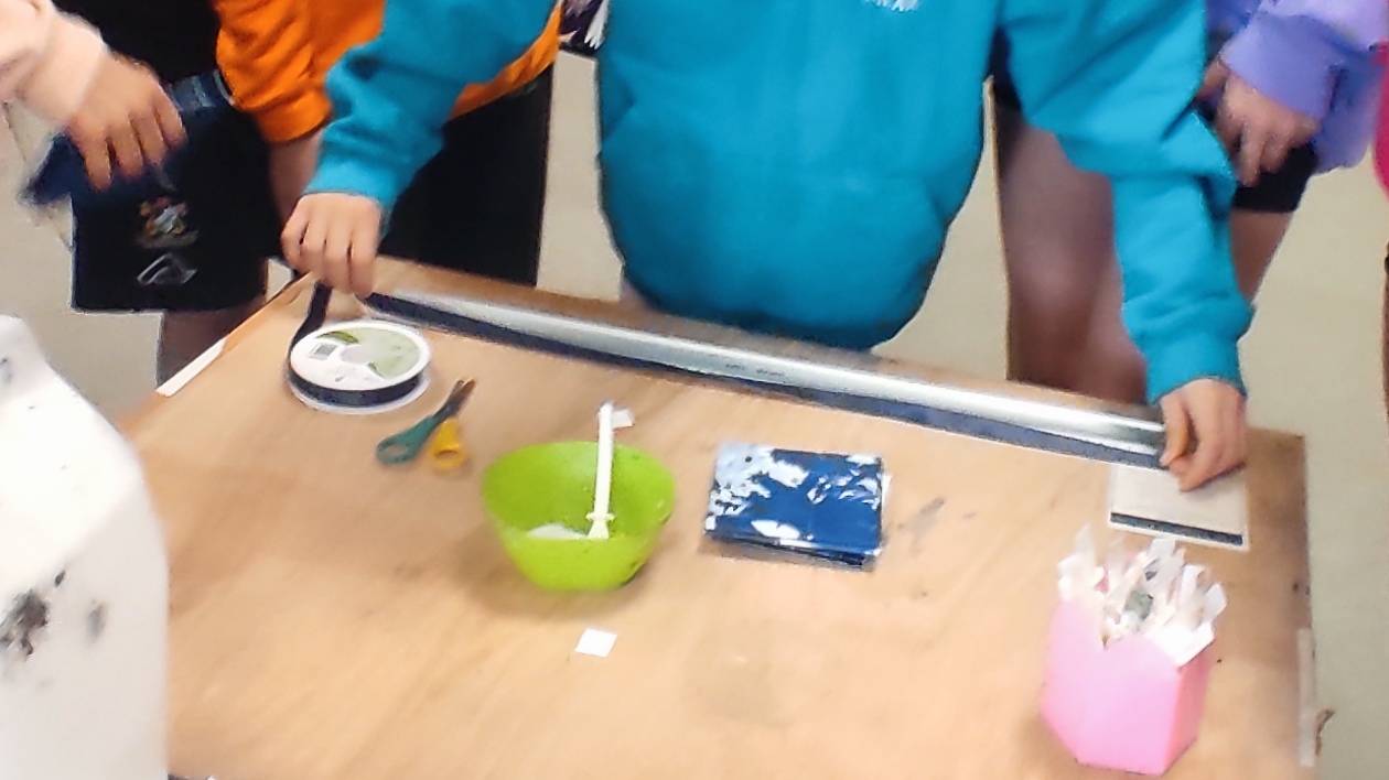 Student measuring up ribbon to tie around the cyanotype