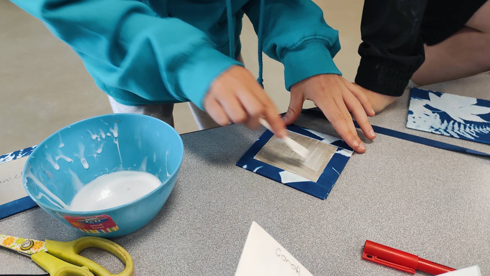 Student putting glue on the back of the covers to glue to the strip