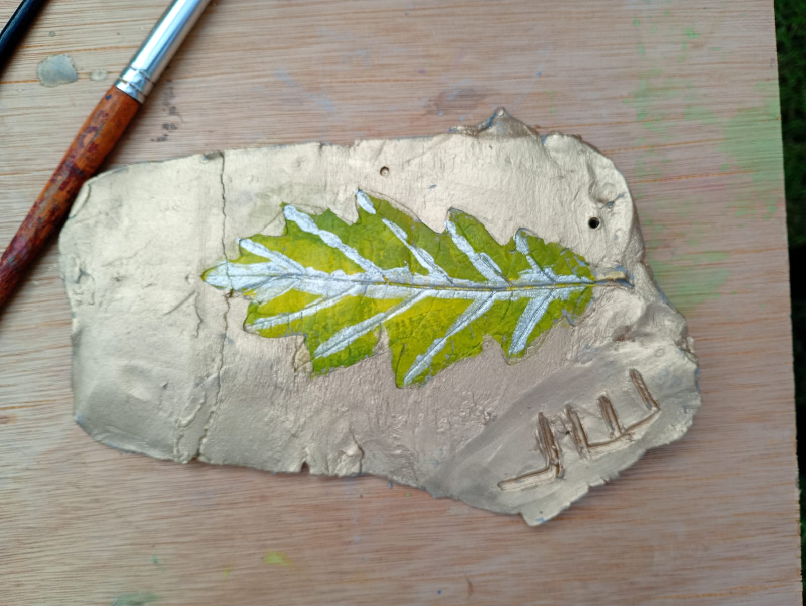 Clay imprint, painted green and silver with gold background