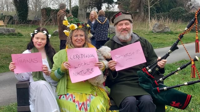Three Friends of Netpool on a bench, holding 3 signs that say THANKS CEREDIGION LOCAL NATURE PARTNERSHIP