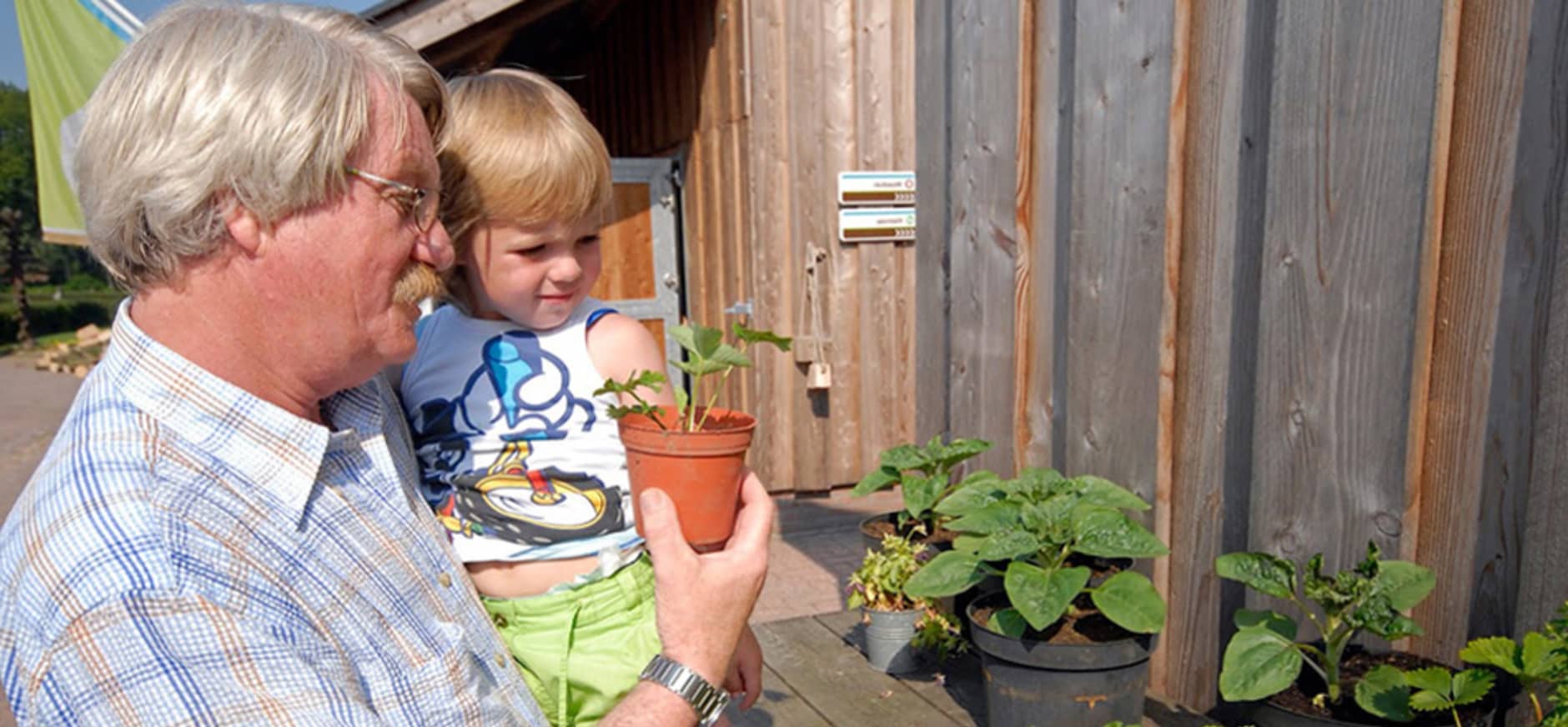 Grootouder met kind bij boerderijwinkel