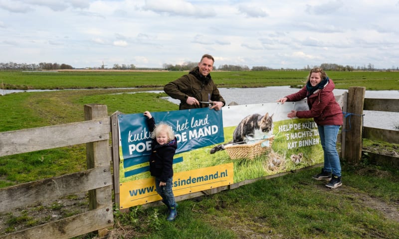 Boswachter Kees Perquin hangt samen met Floor Koornneef van Agrarische Natuurvereniging Vockestaert en haar zoontje Sam (3) de banieren op