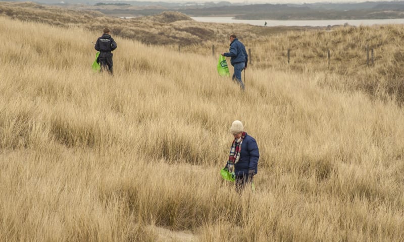 Vrijwilligers ruimen zwerfafval op in de duinen van het Zwanenwater