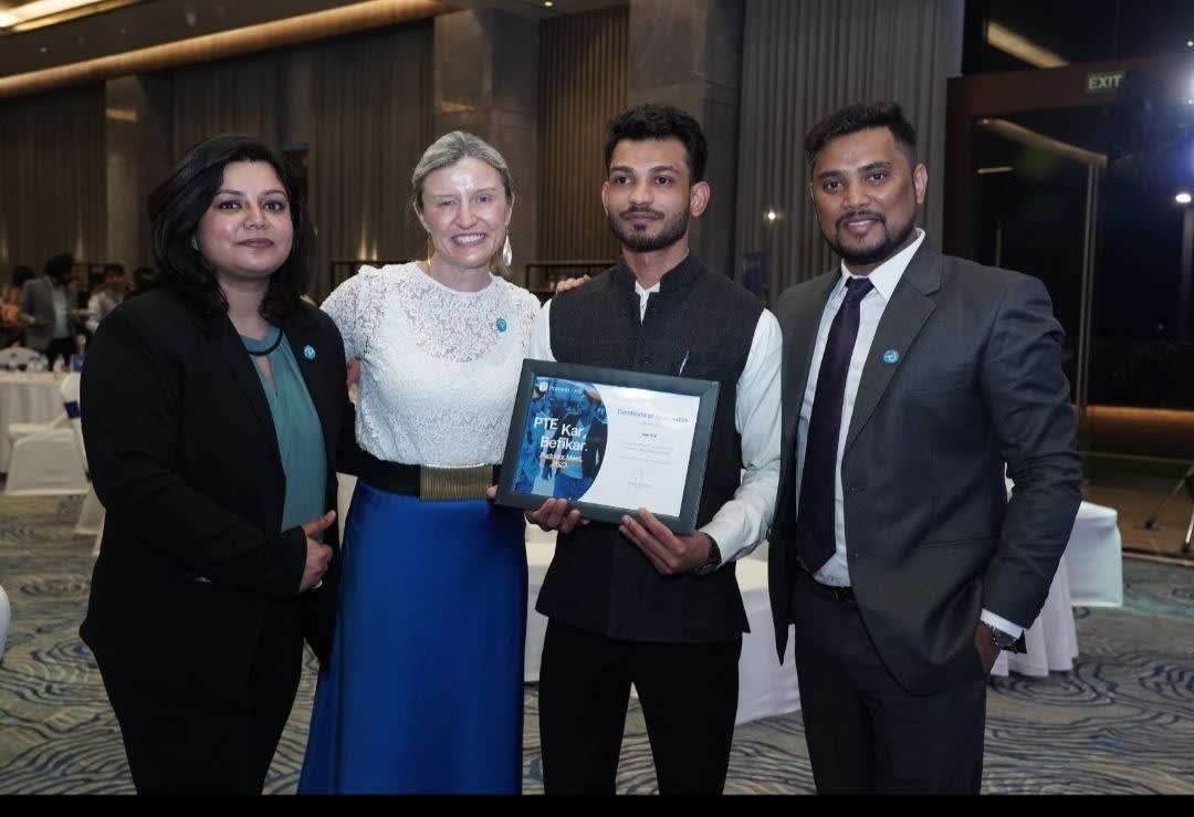 Apex Vouchers team receiving official Pearson PTE partner recognition award certificate on stage.