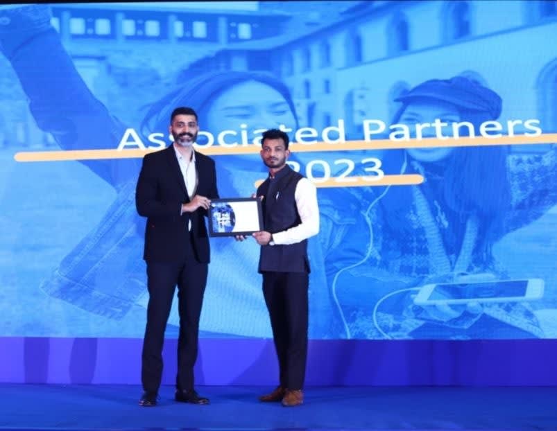 Apex Vouchers representative receiving the Associated Partners 2023 award certificate on stage.