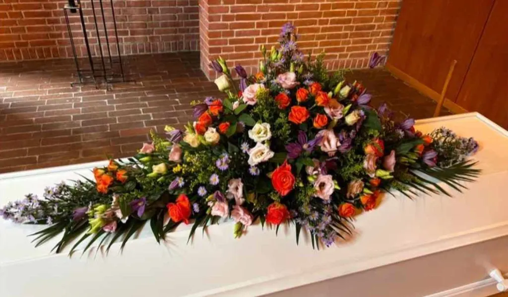 Moderne og farverig kistepynt i kirke – personlig blomsterdekoration til begravelse eller bisættelse I Vejle.