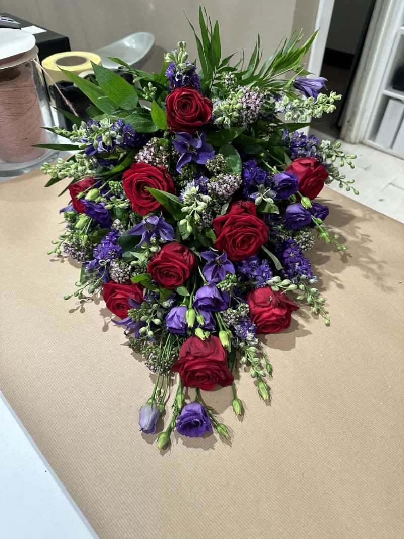 Bårebuket med røde roser og lilla blomster