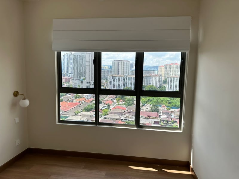 Cream roman blind raised and stacked above a tri-pane window overlooking a dense high-rise city skyline and rooftops