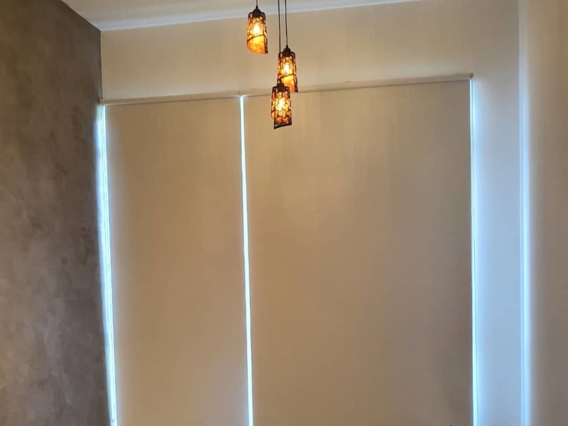 cream blackout roller blinds fully closed across two window panels in a bedroom, blocking any view outside
