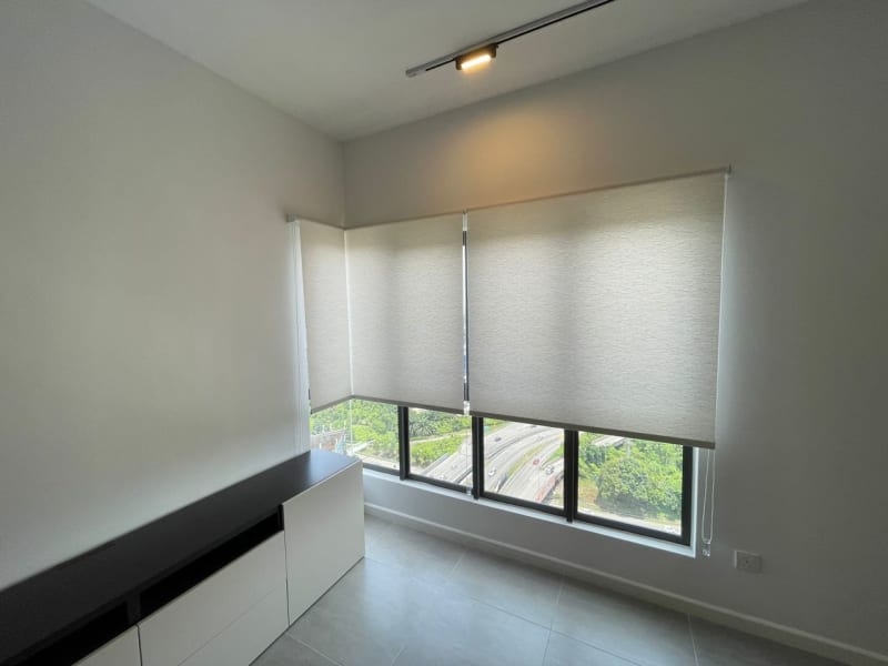textured light gray roller blinds partly lowered in a bedroom, an open gap below revealing a highway and greenery view