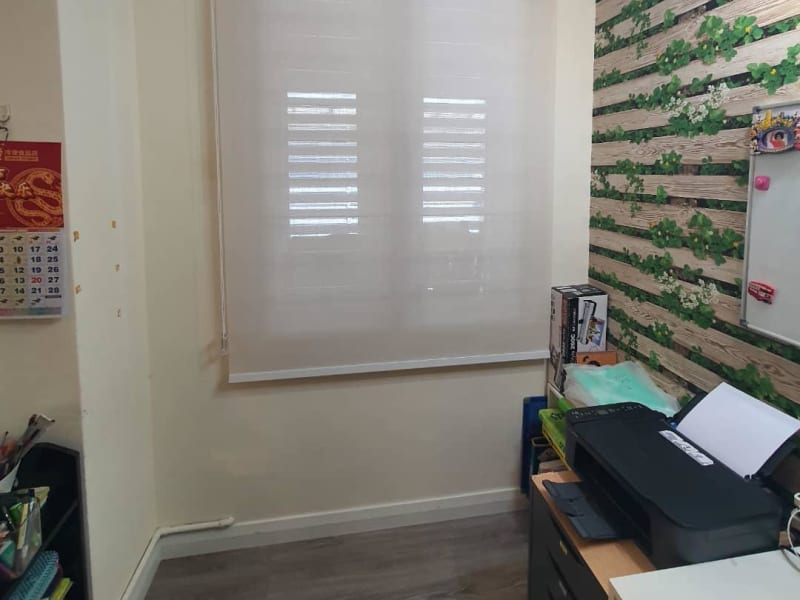 cream light-filtering roller blinds lowered in front of venetian blinds, their slats faintly visible through the fabric