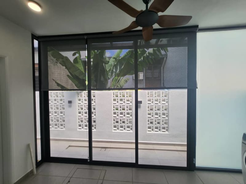 charcoal sunscreen roller blind partly lowered over a sliding glass door, banana leaf plants visible below
