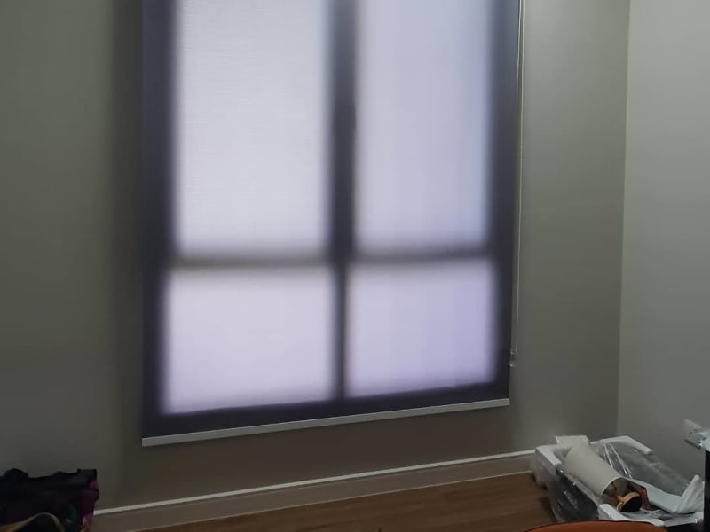 dark charcoal sunscreen roller blinds lowered over a window, the frame and mullions faintly visible through the mesh