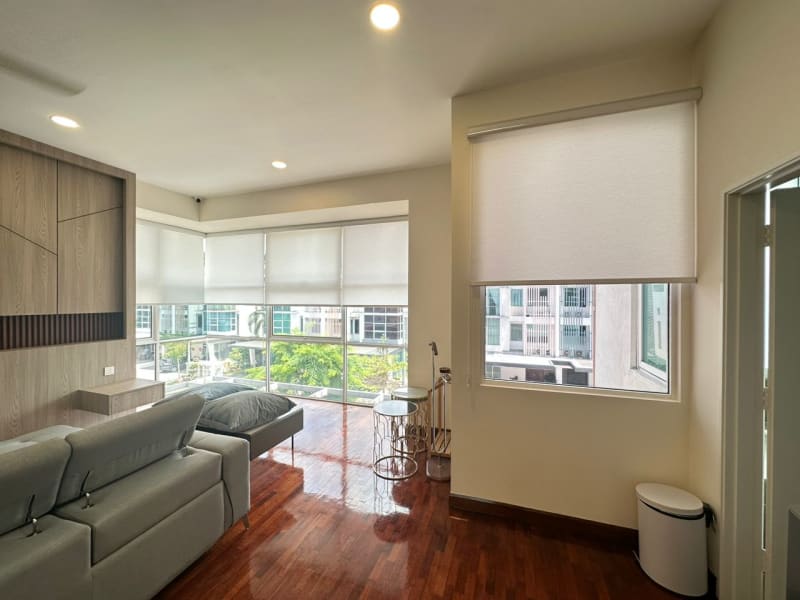 cream light-filtering roller blinds lowered across a corner window and an adjacent wall window in a living room