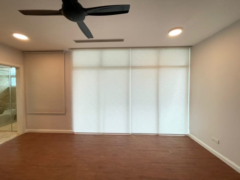 cream light-filtering roller blind lowered over a sliding glass door, a smaller side window raised partway