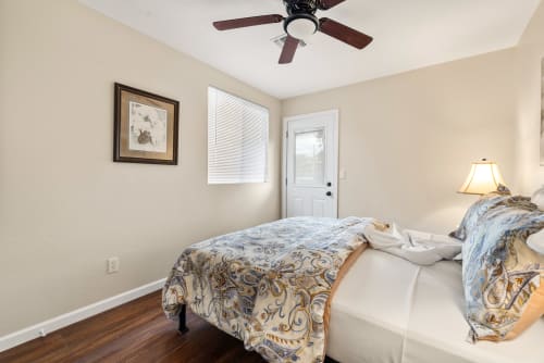 Bedroom three offers a cozy queen-sized bed with soft linens and stylish decor, providing a relaxing retreat. The room is bright and airy, thanks to a large window and a private door that opens directly to the backyard, enhancing the sense of tranquility and connection to nature.