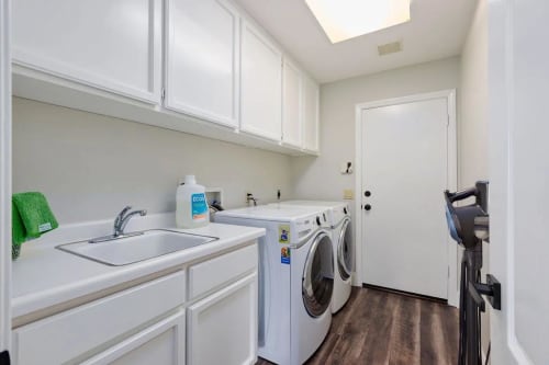 Fully equipped laundry room with front load washer & dryer, utility sink, and storage.