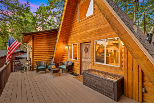 Large front deck with stunning pine views, perfect for stargazing, enjoying a relaxing drink, watching the sunrise, and savoring a complimentary hot beverage.