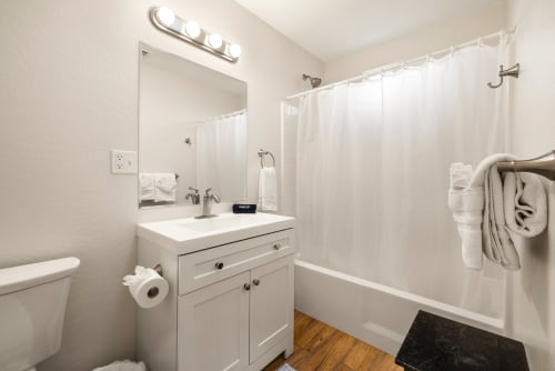 Bedrooms two and three share a spacious full bathroom featuring a combination shower and tub, complemented by a sleek vanity with ample counter space. The bathroom's modern design and soft lighting create a functional yet inviting space for guests or family members.