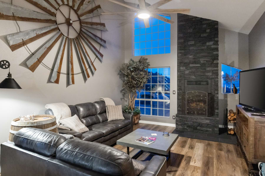 East-Wing Living Room with 65” Smart TV, two leather sofas, xl bean bag, floor to ceiling wood burning fireplace, and work station. Uniquely decorated with pieces from local artists