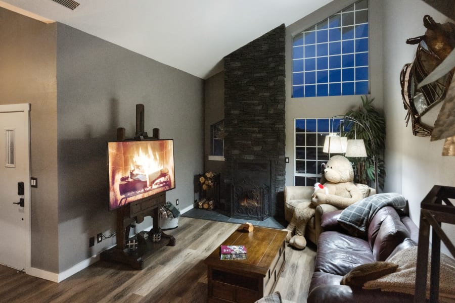 West-wing Living Room with leather queen pullout sleeper sofa, large cuddle sleeper chair with twin pull out , bean bag, 65” Smart Tv, decor from local artists, wood stove set in ceiling to floor stone surrounding. 